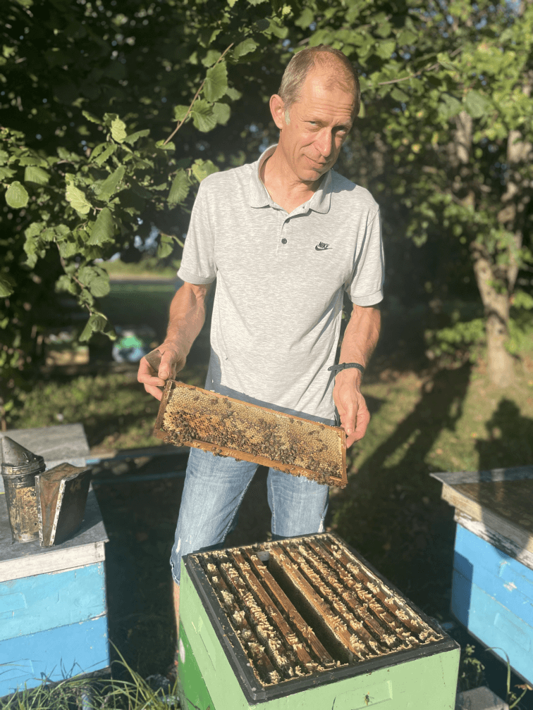 Beekeeper Arunas standing with a honeycomb in his hands