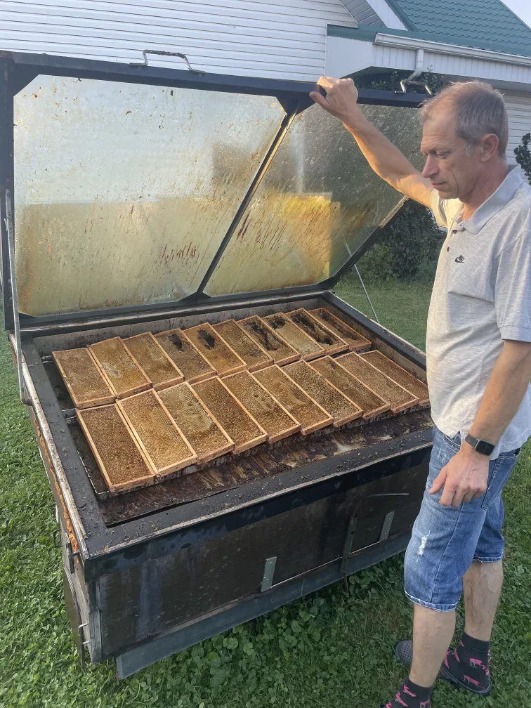 Beekeeper Arunas standing next to his hand-made wax melter